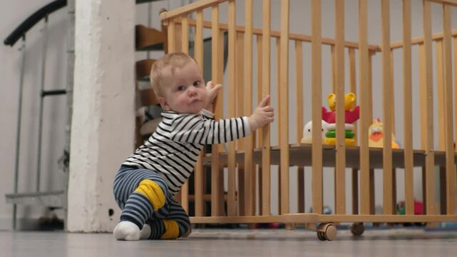 Infant child learning to crawl and push playpen at home. Real kid's life at home. Little boy practicing crawling with playpen. Happy baby development improving skills in early childhood