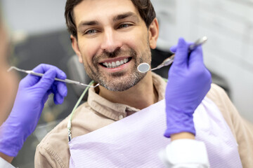 Closeup shot of dentist examining male patients teeth in dental clinic. Man having his teeth...