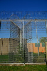 Fototapeta premium High security fence with spiky Nato wire rolls on top at a German prison in Hanover, Lower Saxony, Germany. Barbed wire to stop prisoners from escaping.