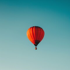 Fototapeta premium A vibrant red hot air balloon floating in the clear blue sky, symbolizing freedom and adventure.