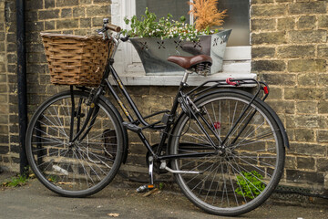 Fototapeta premium Traditional style bicycle with a wicker basket on the front locked up outside a terraced house in Cambridge