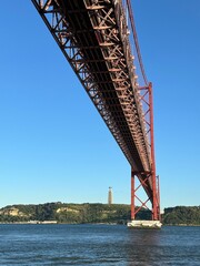 Detailed view looking up at the April 25 Bridge in Lisbon Portugal with a clear blue sky background. 