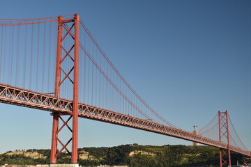Detailed view looking up at the April 25 Bridge in Lisbon Portugal with a clear blue sky background. 