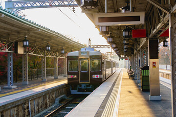 Local train departing from platform of Arashiyama station  in morning autumn.