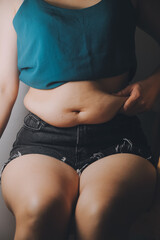 Fototapeta premium fat woman, fat belly, chubby, obese woman hand holding excessive belly fat with measure tape, woman diet lifestyle concept