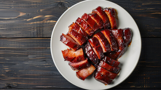 Char siu, sliced barbecue pork, is resting on a dark wooden surface