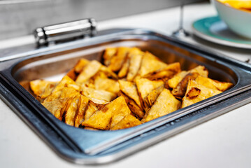 Lots of fried samosas in a metal tray.