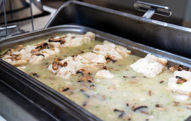 White fish with mushrooms in a metal container.