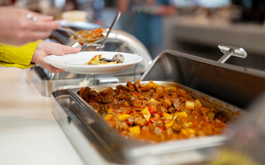 Woman puts food on her plate at the buffet. All-inclusive system.
