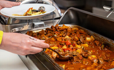 Woman puts food on her plate at the buffet. All-inclusive system.