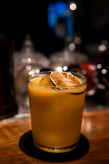 Isolated cocktail with gin. Iced alcoholic drink and sweet fruit. Blurred background lemon on top closeup orange glass. bar setting. Gin cocktail with bokeh background