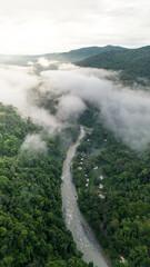 Vertical aerial shot of the Pacuare River bed surrounded by trees in the middle of the Caribbean jungle with mountains and fog in the background in the province of Limón in Costa Rica
