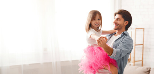 Father and daughter having dance lesson, dad teaching little girl dancing at home