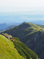 A verdant mountain ridge is visible in the foreground with hazy hills and wide valleys stretching...