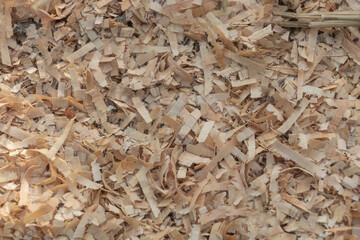 A close-up of wood chips and shavings, showcasing the intricate patterns created by their cut surfaces. The texture is rich with natural grain details