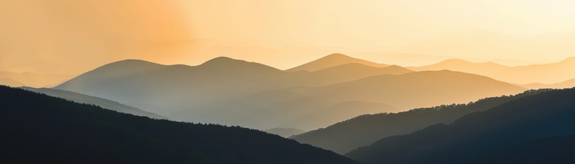 Fototapeta premium Beautiful sunset over mountain landscape with layers of mist and soft orange glow in the sky, perfect for nature and travel-themed projects.