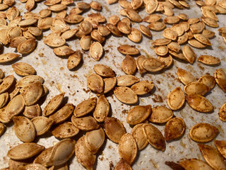 Roasted pumpkin seeds spread out on a baking sheet ready for cooling after a flavorful seasoning mix