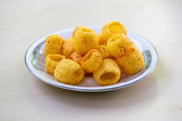 Delicious spicy potato ring chips or aloo chips on a white plate on a light wooden surface.