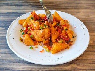 a plate of crispy Tahu Cabe Garam (chili salt tofu) snacks. Spicy fried tofu sprinkled with dried red and green chilies