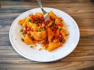 a plate of crispy Tahu Cabe Garam (chili salt tofu) snacks. Spicy fried tofu sprinkled with dried red and green chilies