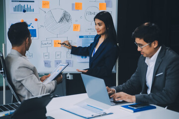 Group of confident business people point to graphs and charts to analyze market data, balance sheet, account, net profit to plan new sales strategies to increase production capacity.