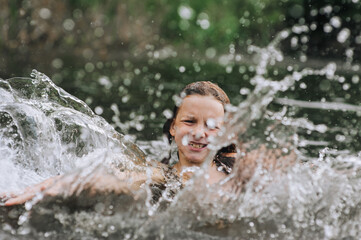 Fototapeta premium Little happy girl, smiling child jumping, having fun, laughing, spinning, swimming in water on sea, in lake on summer holidays. Photography, portrait, lifestyle, childhood concept.
