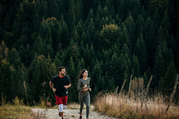 Fototapeta premium Shot of a young couple admiring view while out for a workout on a mountain road