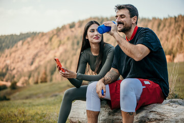 Athletes couple resting after hard workout session outdoors. Fitness, sport, exercising and healthy lifestyle concept