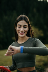 Female runner synchronizing wireless earphones with a smart watch. Preparing for trail running outdoors at sunrise