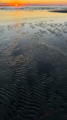Sunset over the sea. Sea beach at the setting sun.