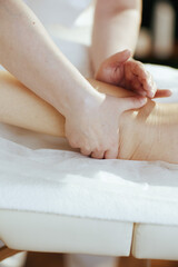 Closeup on massage therapist in spa salon massaging clients leg