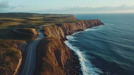 Fototapeta premium Breathtaking Aerial View of Winding Coastal Road Hugging Rugged Cliffs and Crashing Waves