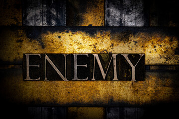 Enemy text with on grunge textured copper and gold background 