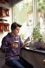 Man, headphones and coffee for reading book at cafe, literature and student to study on campus....