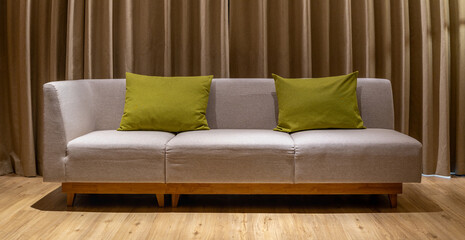 Sofa in a contemporary room with brown leather upholsteryand and soft pillows, against a curtain backdrop, creating a comfortable and stylish interior