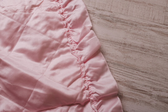 A pink bedspread featuring ruffles.