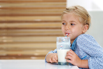 Girl, child and drinking milk in home, nutrition and vitamin d liquid for brain development. Female...