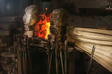 Flame in a forge with handmade bellows and a set of vintage tools in an old rural workshop....