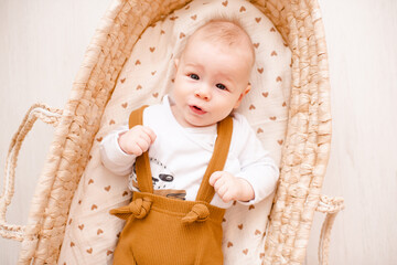 Funny baby boy wake up in straw baby bassinet close up top view. Good morning. Childhood.