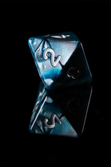 a blue and white marbled eight-sided D8 dice with white numbers showing the number two on a black background with a reflection