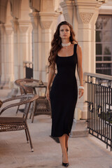 beautiful woman with dark long hair in elegant clothes with accessories posing in classic villa