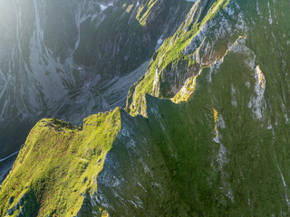 Fototapeta premium Aerial view of mountains with grass and rocks in Switzerland. Hiking in tranquil nature. Background with alpine pattern.