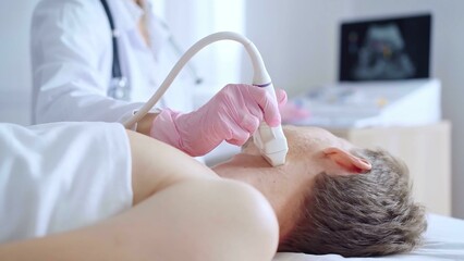 Doctor woman with pink medical gloves performing neck ultrasound exam on male patient. Thyroid gland examination. Medicine service concept