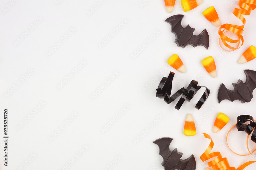 Poster halloween side border of black, white and orange color candy and ribbon. overhead view on a white ba