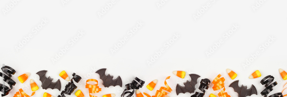 Poster halloween bottom border of black, white and orange color candy and ribbon. top view on a white banne