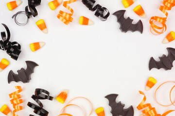 Halloween frame of black, white and orange color candy and ribbon. Overhead view on a white background with copy space.