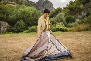 Fototapeta premium Mature japanese woman set up a tent in nature ready for camping