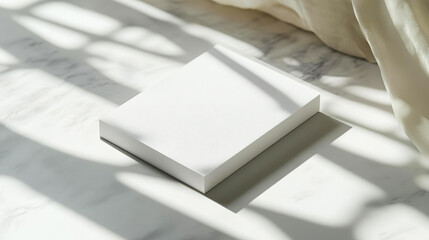 A neatly wrapped white box lies on a marble surface, bathed in natural light with soft shadows, perfect for product packaging, gift presentations, or minimalist design showcases,