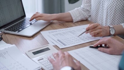 Fototapeta premium Professional female bookkeeper or auditor are working on business finances with a colleague, using calculator and laptop. Finance audit and taxes