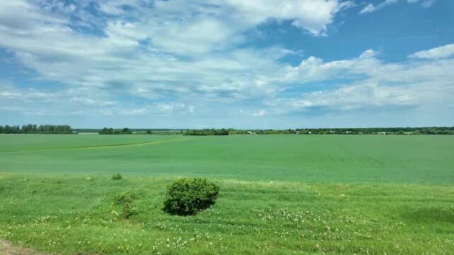 View from the window of endless fields, blue sky with clouds, train travel